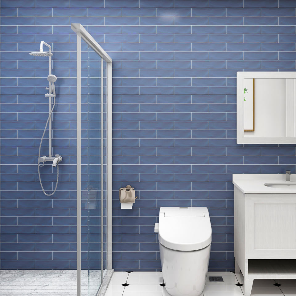 Phòng tắm với tường gạch xanh, vòi sen, bồn cầu trắng và tủ lavabo trắng.
