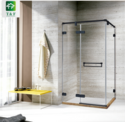 Buồng tắm kính góc vuông với khung viền đen, tường nền gạch xám, bàn vàng đặt bên cạnh.