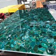 Mặt bàn đá mã não xanh với họa tiết vòng tròn và màu sắc đa dạng, ánh sáng phản chiếu.
