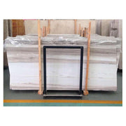 Các tấm đá hoa cương màu trắng xám, xếp trên kệ gỗ, bọc nhựa trong.