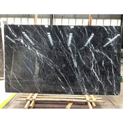 Phiến đá cẩm thạch đen với vân trắng nổi bật, đặt trên kệ gỗ trong nhà xưởng.