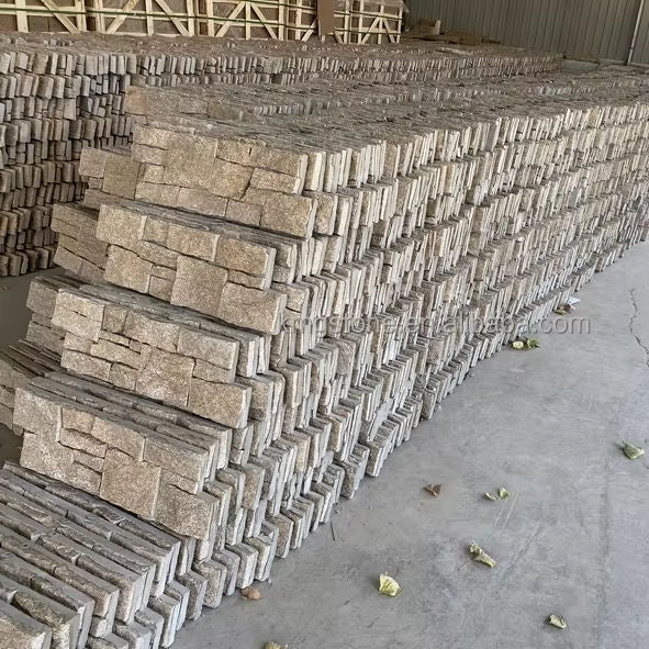 Chồng gạch xếp lớp màu xám nhạt trong nhà kho, nền xi măng, vài chiếc lá rơi trên sàn.
