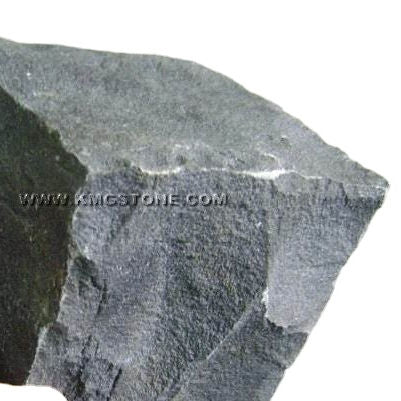 Mảnh đá màu xám đen, bề mặt thô ráp với cạnh sắc nhọn.