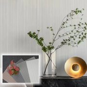Bình thủy tinh có cành cây xanh, đèn vàng trên tủ; tranh nhỏ chồng chất liệu với cây đỏ.