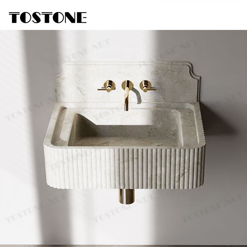 Bồn rửa bằng đá cẩm thạch màu sáng với vòi và tay vặn màu vàng, thiết kế vân sọc đứng.