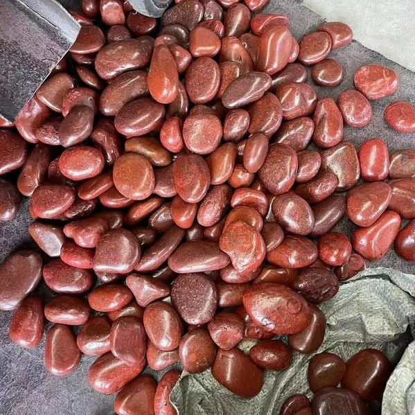 Hình ảnh các viên đá cuội màu đỏ bóng loáng, xếp tập trung trên bề mặt tối.
