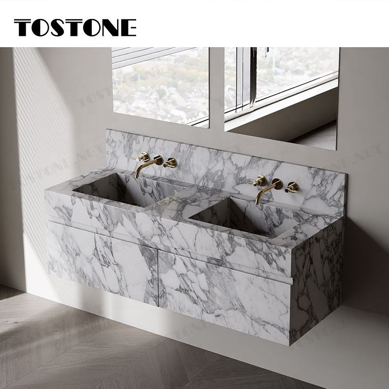 Bồn rửa đôi bằng đá cẩm thạch trắng, vòi vàng, phía trên là cửa sổ lớn.