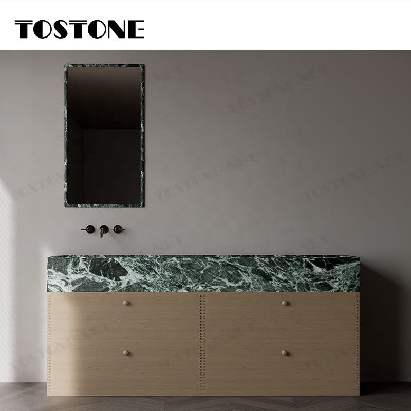 Tủ gỗ với mặt đá cẩm thạch xanh đậm, trên tường là gương hình chữ nhật có viền đá.