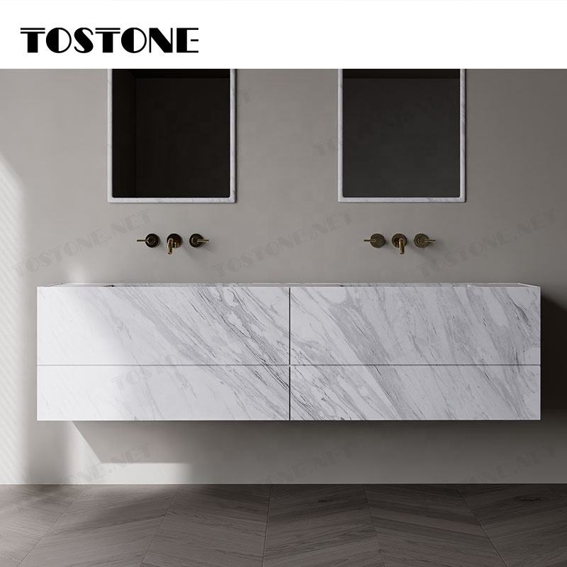 Tủ lavabo treo tường đá trắng vân xám, hai vòi nước đồng trên tường màu xám.