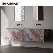 Tủ lavabo treo tường đá vân đỏ và xám, hai vòi nước vàng, nền tường và sàn gỗ tối màu.
