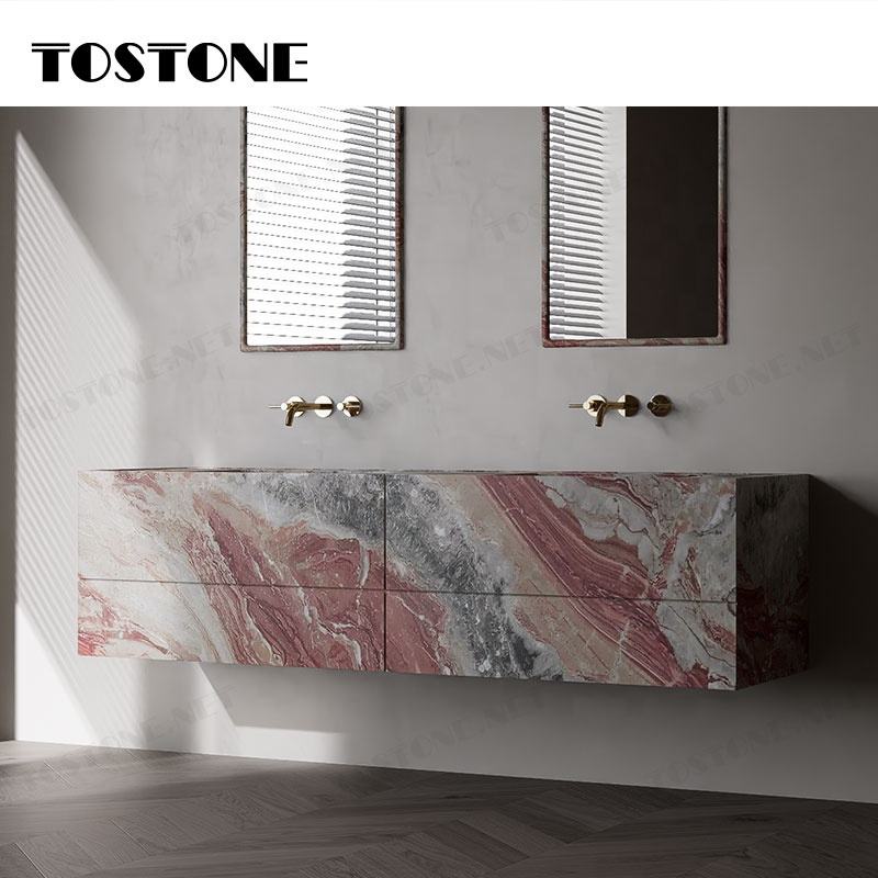 Tủ lavabo treo tường đá vân đỏ và xám, hai vòi nước vàng, nền tường và sàn gỗ tối màu.