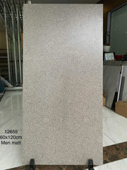 Tấm gạch men mờ màu xám, kích thước 60x120 cm, đứng trên giá đỡ trong phòng trưng bày.