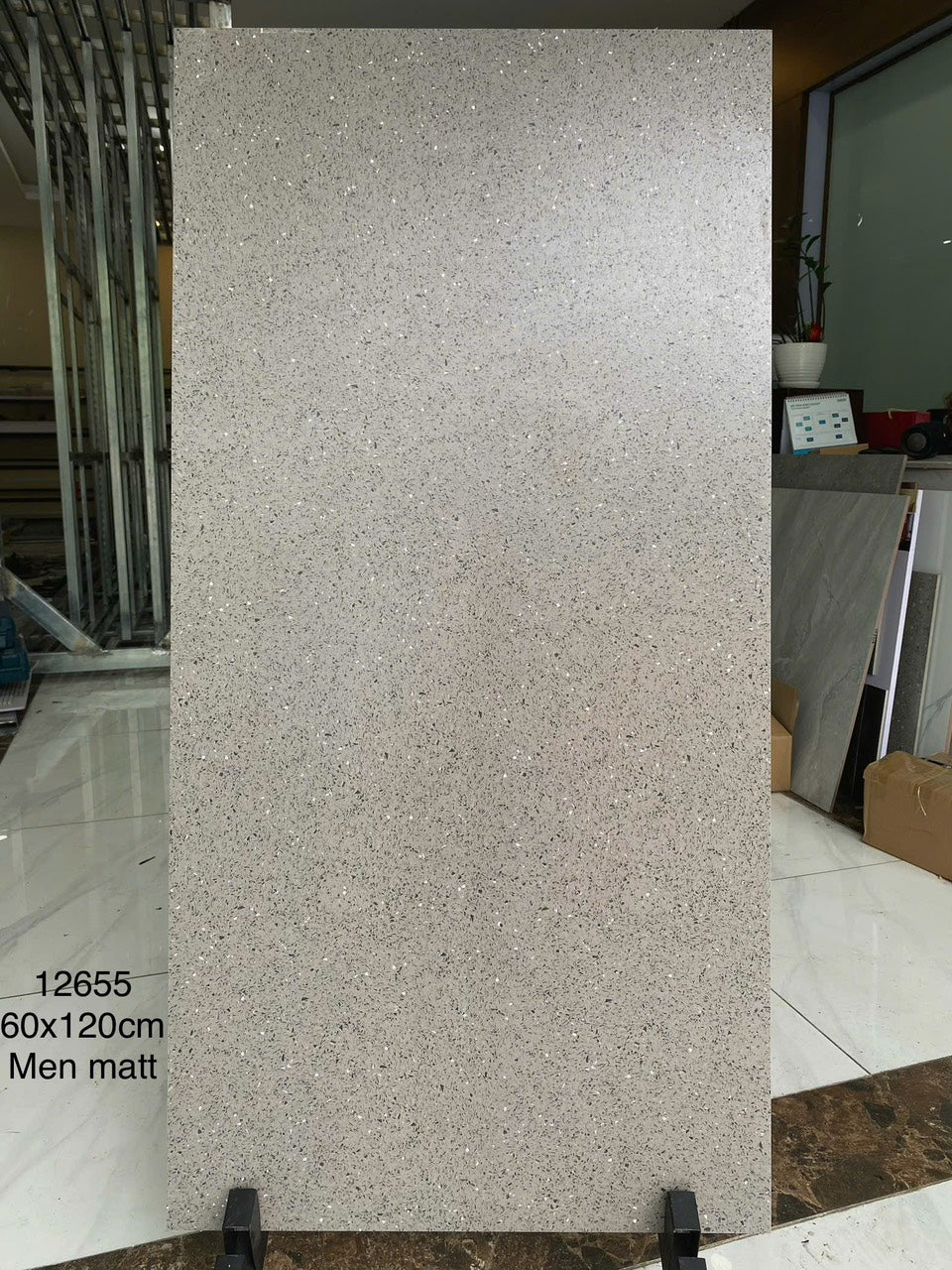 Tấm gạch men mờ màu xám, kích thước 60x120 cm, đứng trên giá đỡ trong phòng trưng bày.