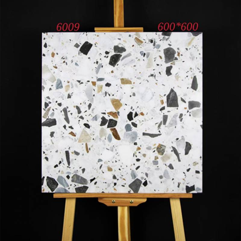Tấm gạch terrazzo vuông 600x600mm, nền trắng, chấm màu đen và nâu, trên giá vẽ gỗ.