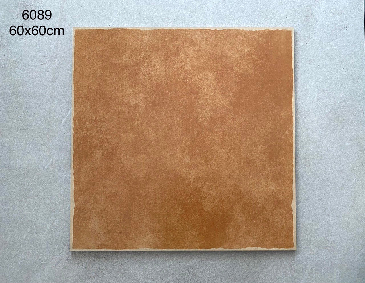 Gạch vuông màu nâu đất, kích thước 60x60cm, nền xám nhạt.