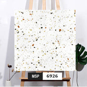 Bức tranh terrazzo với nền trắng, họa tiết đa sắc cam, xanh lá, đen, trên giá vẽ gỗ.