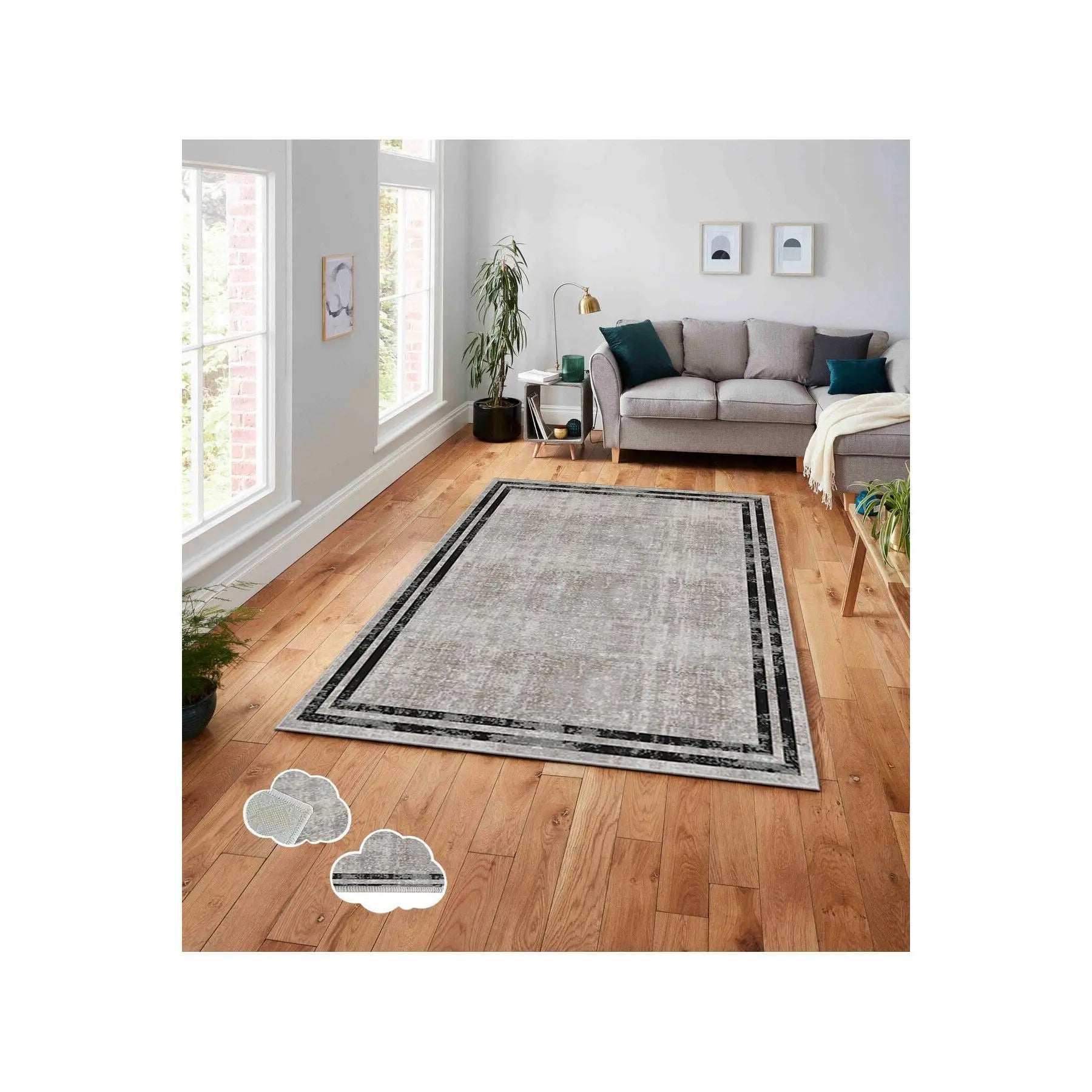 Phòng khách với ghế sofa xám, thảm lớn xám nhạt trên sàn gỗ, và cây trang trí bên cửa sổ.