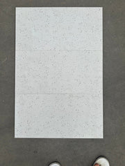 Ba viên gạch trắng với các đốm nhỏ, xếp trên nền xám, có phần ngón chân phía dưới.