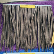 Các sợi rơm màu nâu xếp thẳng đứng trên nền thảm tím, có bảng hiệu màu vàng phía trên.