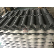Tấm lợp sóng màu xám đen xếp chồng, bề mặt nhám, trong không gian nhà xưởng.