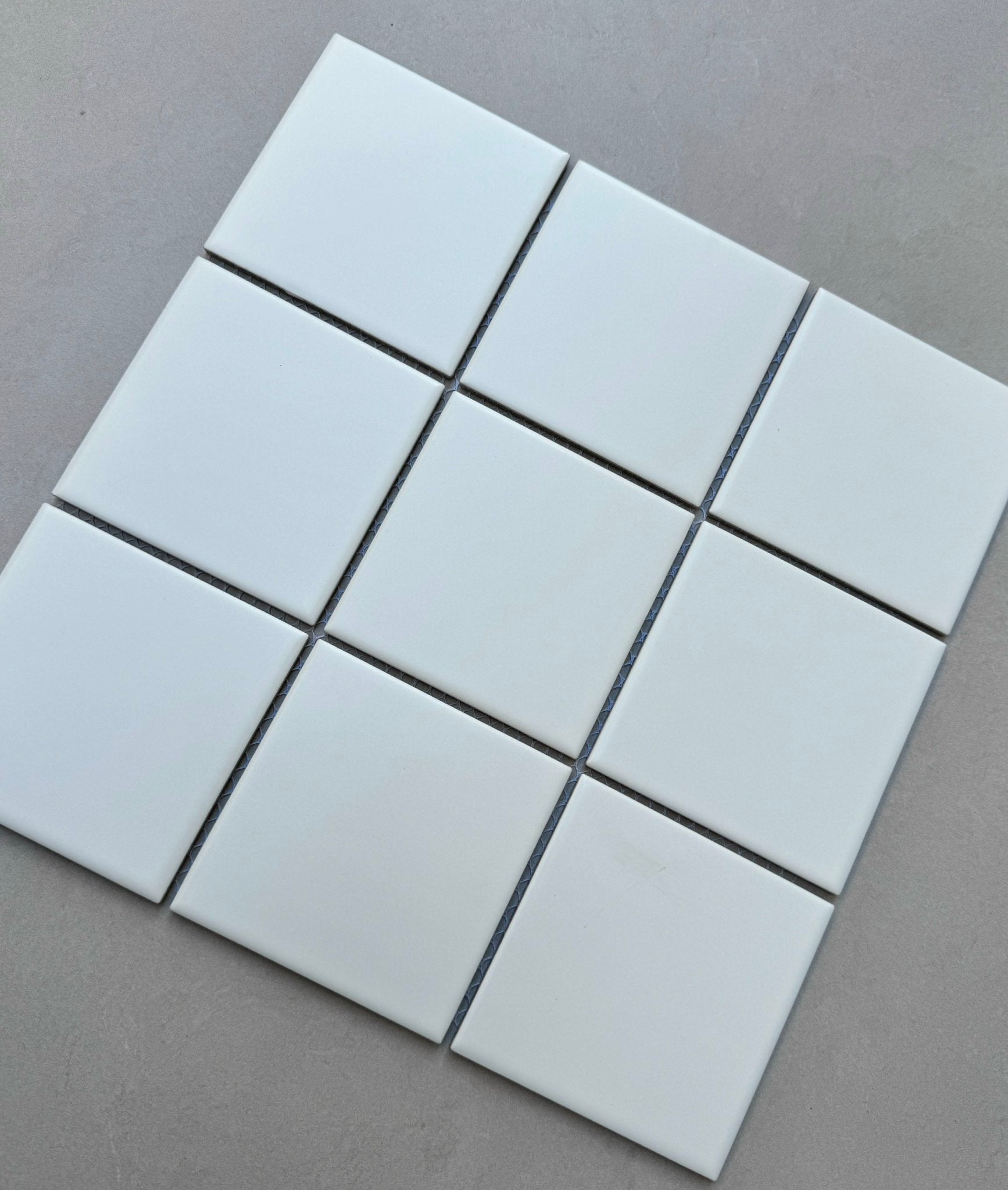 Chín viên gạch trắng hình vuông xếp 3x3 trên nền xám nhạt.