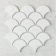 Gạch trắng hình vảy cá xếp trên nền đá cẩm thạch, tạo họa tiết đối xứng.